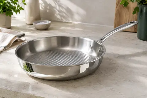 Poêle grill Lagostina en inox 18/10, à fond texturé et finition miroir, posée sur un plan de travail clair.
